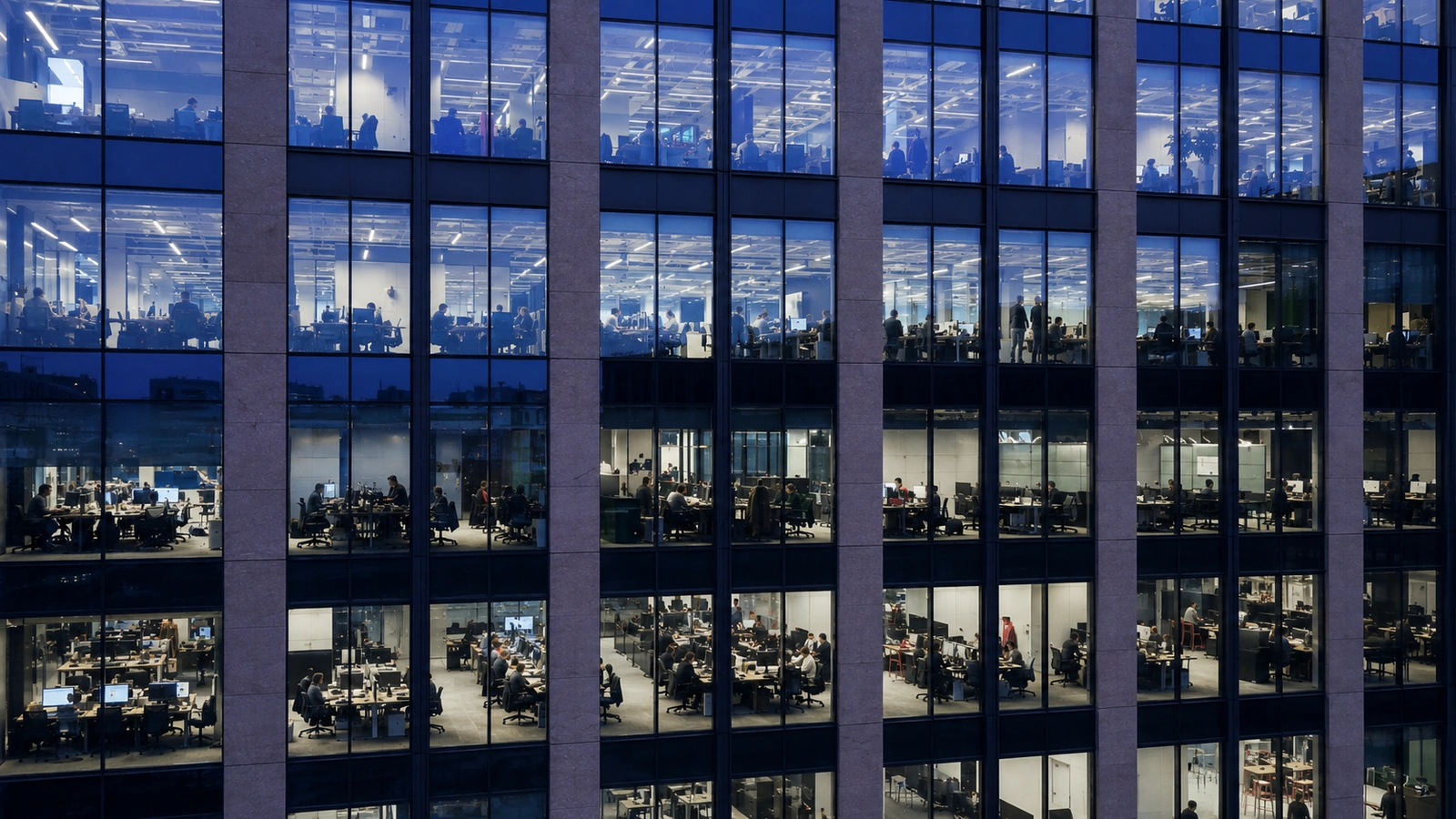 Busy office building lit through many windows at night