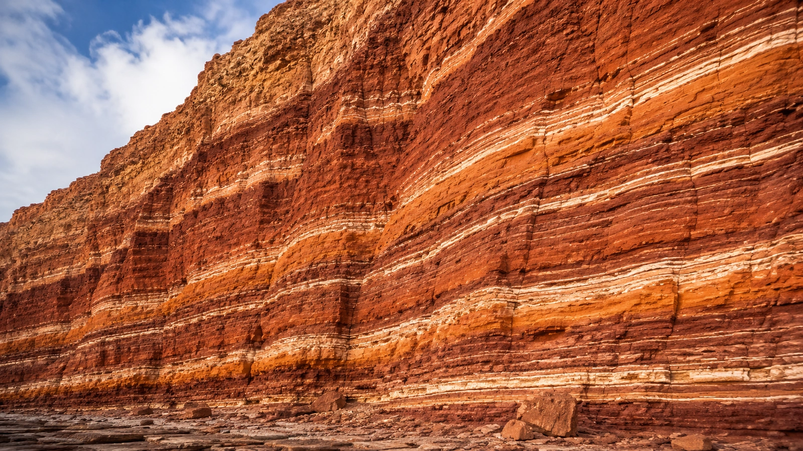 Layered red rock cliff under a blue sky