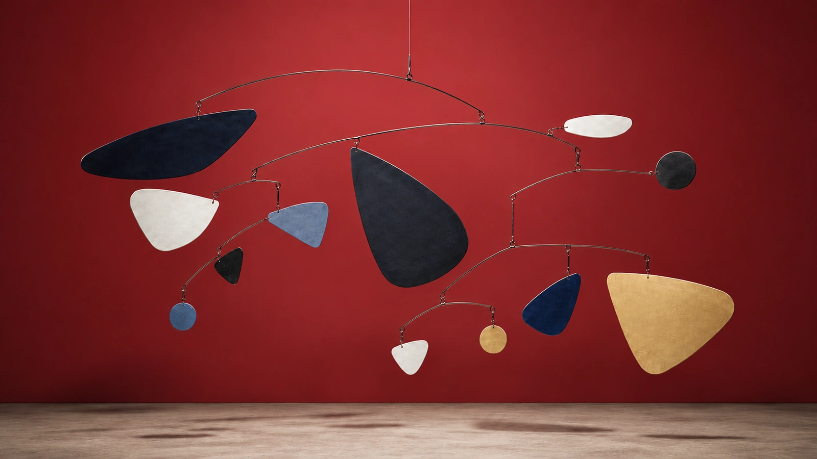 Balanced mobile sculpture hanging against a red gallery wall